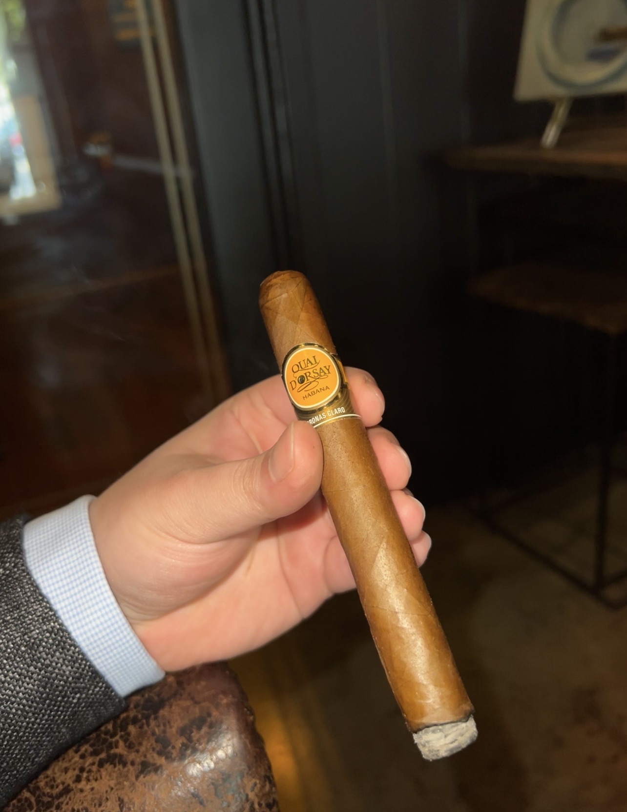A Quai d’Orsay Coronas Claro cigar held in hand, showing its gold band and ash